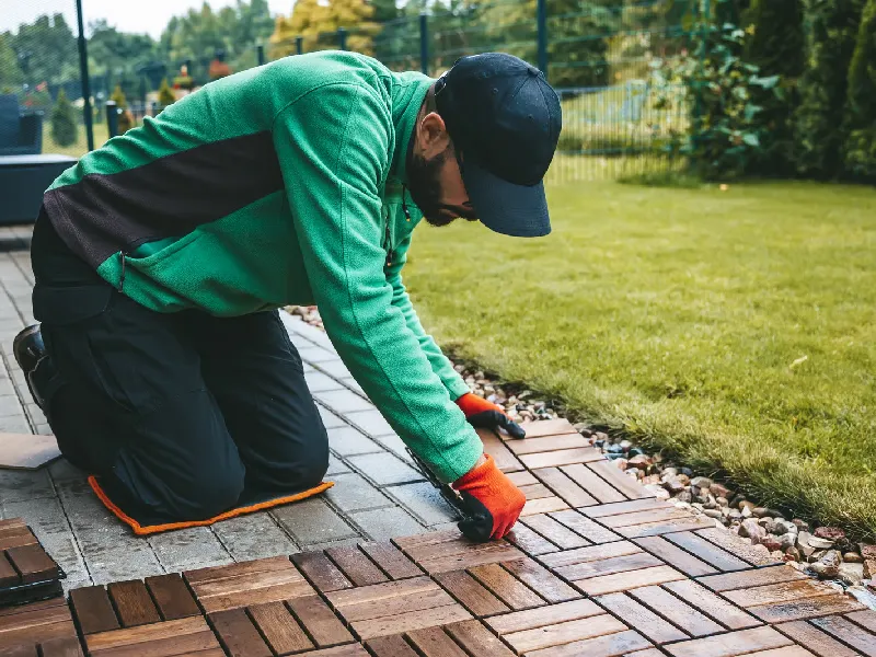 A man carefully installing wooden floorboards on the terrace